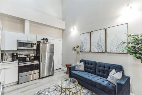 a living room with a blue couch and a kitchen at Large Bi-Level 2BR Loft in Old City that Sleeps 8 in Philadelphia