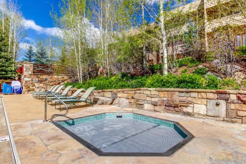 a swimming pool with two chairs and a stone wall at Sun Vail 24A in Vail