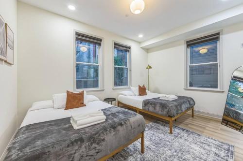 a bedroom with two beds and a bench and windows at New 2BR Across from Fairmount Park - 10 Mins to DT in Philadelphia