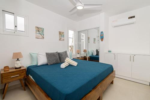 a bedroom with a blue bed in a white room at Modern 2BR Condo with Pool in Bayahibe