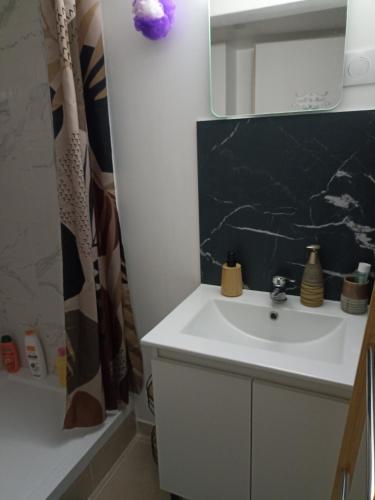 a bathroom with a white sink and a mirror at La Dune Bohème chic in Saint-Maurice-de-Beynost