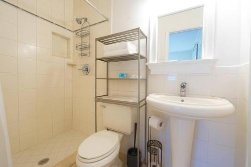 een witte badkamer met een toilet en een wastafel bij Lighthouse Point Poolside Retreat in Floresta Estates