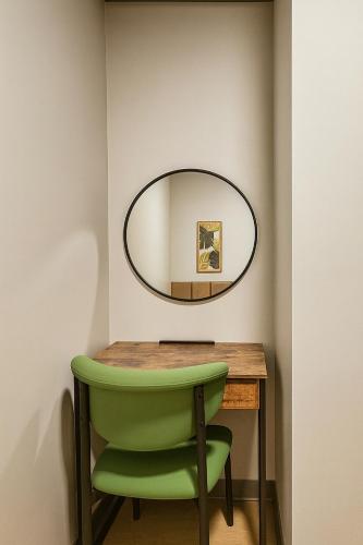 a green chair sitting next to a table with a mirror at CityNest Hotel in New York