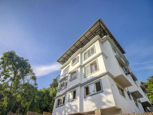 a white building with a roof on top of it at Hotel O Muktesh Chandra in Goa