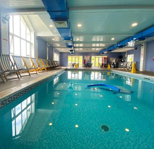 a large swimming pool with chairs in a building at Modern 2017 model Delta Sienna static caravan in Clarach Bay in Aberystwyth