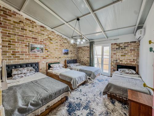 a room with three beds and a brick wall at Komolon in Tashkent