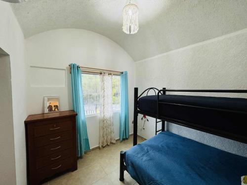 a bedroom with a bed and a dresser and a window at Casa con alberca cerca de playas in Ixtapa