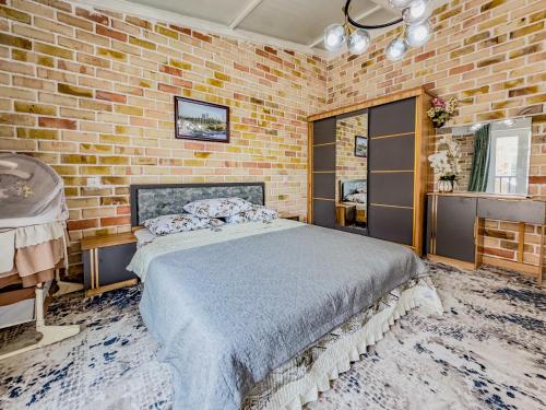 a bedroom with a bed and a brick wall at Komolon in Tashkent