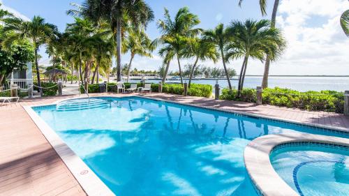 a swimming pool with palm trees and the ocean at Kaibo Escape - Beachfront Condo with a Special Last-Minute Rate in Driftwood Village