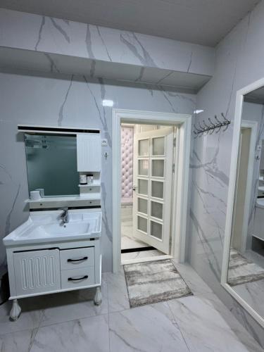 Un baño blanco con lavabo y espejo. en Luxury Central Apartments Samarkand, en Samarkand
