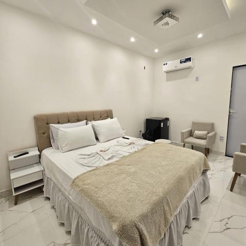 a bedroom with a large bed and a chair at Casa tia Rosa, hospedagem familiar Guapimirim RJ in Guapimirim