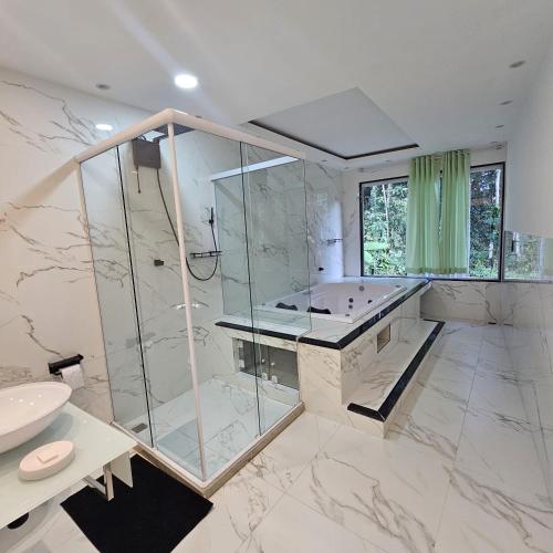 a large bathroom with a shower and a sink at Casa tia Rosa, hospedagem familiar Guapimirim RJ in Guapimirim