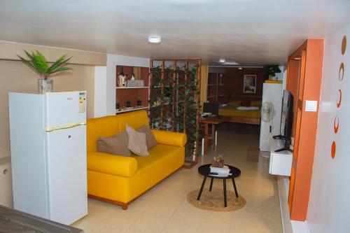 a living room with a yellow couch and a kitchen at Studio City Center in Mindelo