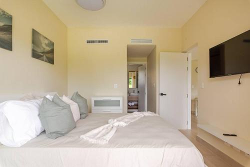 una camera da letto con un letto bianco con una TV a schermo piatto di NOK Amazing 1 BR by Vistacana Rentals a Pueblo Bávaro
