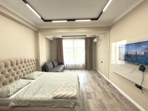 a bedroom with a bed and a couch and a tv at Action in Bishkek