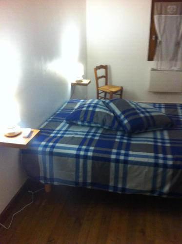 - une chambre avec un lit à carreaux bleu et un bureau dans l'établissement L'Ombrière, à Saint-Thomas-de-Cônac