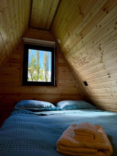 a bed in a log cabin with a window at Mestia Sunrise Cottage, 1BR Mountain Stay Svaneti in Mestia