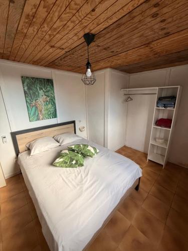 Un dormitorio con una cama blanca con techo de madera. en Villa La Cruzanelle, en Sainte-Rose