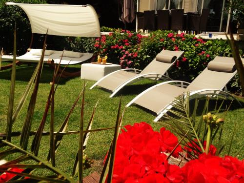 a group of white chairs and red flowers in a yard at Villa La Clef Des Champs in Chailly-en-Bière