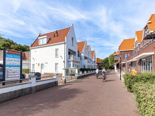 a person riding a bike down a street with buildings at Holiday Home in Koudekerke near the Beach in Koudekerke