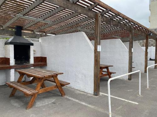 a patio with two picnic tables and an outdoor oven at Descansa frente al mar y disfruta todos los días del año en Neohaus in La Serena