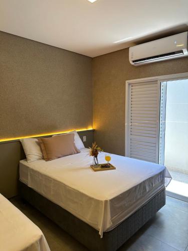 a bedroom with a large bed with a air conditioner on the wall at Flat Bélgica Piscina e Conforto in Olímpia