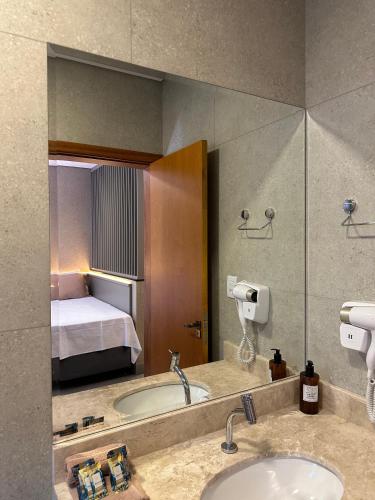 a bathroom with a bed and a sink and a mirror at Flat Bélgica Piscina e Conforto in Olímpia