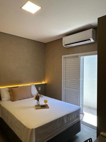 a bedroom with a large bed with a air conditioner at Flat Holanda Piscina e Conforto in Olímpia