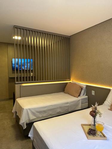 a bedroom with two beds and a table with flowers on it at Flat Holanda Piscina e Conforto in Olímpia