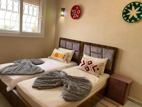 two beds with blankets and pillows in a bedroom at taghoba surf house in Tamraght Ouzdar