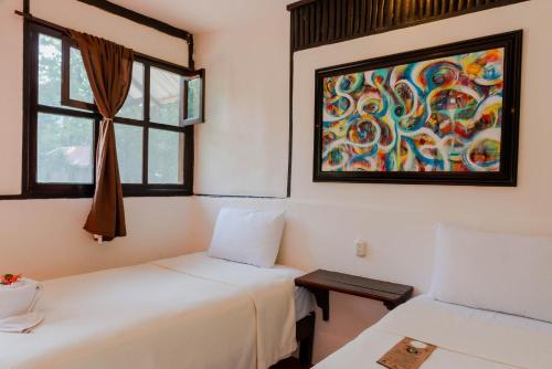 two beds in a room with a painting on the wall at Cabañas Kin Balam Palenque in Palenque
