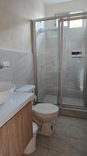 a bathroom with a toilet and a glass shower at CASA BLANCA HORTENCIA in Sucúa