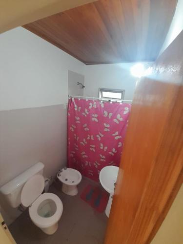 a bathroom with two toilets and a red shower curtain at La Casa de Don Fermín in Federación