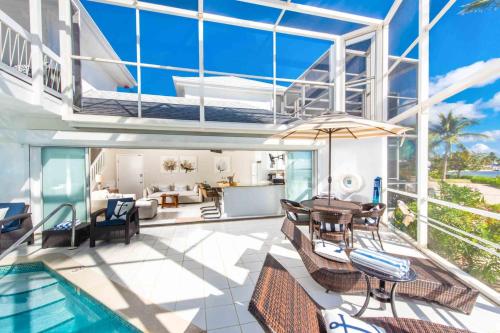 a house with a swimming pool and a dining room at Pools of the Kai 6 - Beachfront Condo with Private Pool Atrium, Modern Kitchen, and Outdoor Grill in Driftwood Village