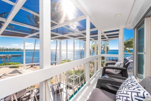 a balcony with chairs and a view of the ocean at Pools of the Kai 6 - Beachfront Condo with Private Pool Atrium, Modern Kitchen, and Outdoor Grill in Driftwood Village