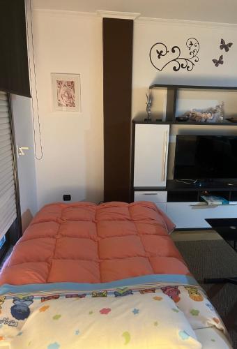 a bed with an orange comforter in a bedroom at Pegadas no mar in Ribeira