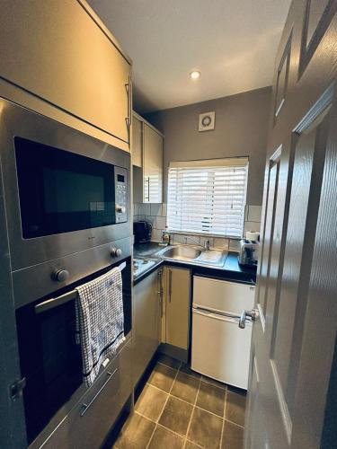 a small kitchen with a sink and a microwave at Wessex House in Basingstoke