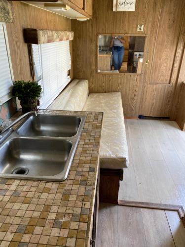 una cocina con fregadero y una persona en el espejo en Affordable Rooms in RV Trailer, en Los Ángeles