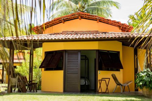 a yellow house with a table and chairs outside at Villa Côté Sud Pousada De Charme in São Miguel dos Milagres