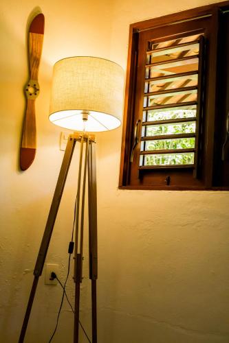 a lamp in the corner of a room with a window at Villa Côté Sud Pousada De Charme in São Miguel dos Milagres