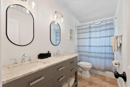 y baño con lavabo, aseo y espejos. en Luxury Getaway In Naples Pool Elegant Remodel, en Naples