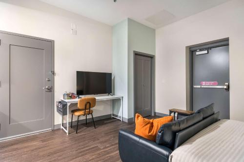 ein Schlafzimmer mit einem Bett und einem Schreibtisch mit einem Fernseher in der Unterkunft Accessible Comfort Near Atrium & Downtown Macon in Macon