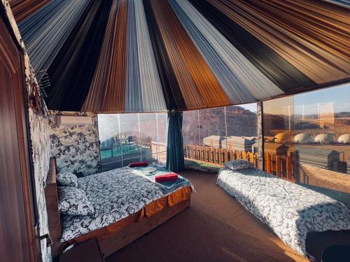 Un dormitorio con dos camas y una gran ventana. en Rum Awaad luxury camp, en Wadi Rum