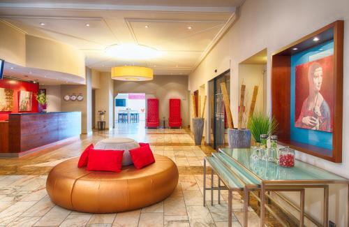 a lobby with a table and a large ottoman at Leonardo Hotel Karlsruhe in Karlsruhe