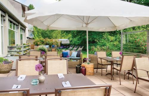 a patio with tables and chairs and an umbrella at Leonardo Hotel Karlsruhe in Karlsruhe
