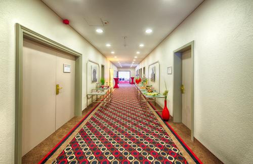 a hallway with a red carpet on the floor at Leonardo Hotel Karlsruhe in Karlsruhe