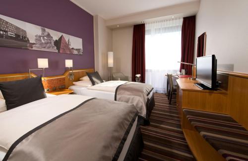 a hotel room with two beds and a flat screen tv at Leonardo Hotel Karlsruhe in Karlsruhe