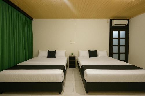 パダンにあるHotel amazon beachの緑のカーテンがかかった部屋にベッドが2つ