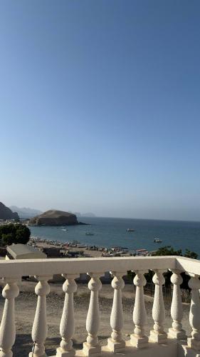 a white fence with a beach in the background at Qantab village apartment in Muscat