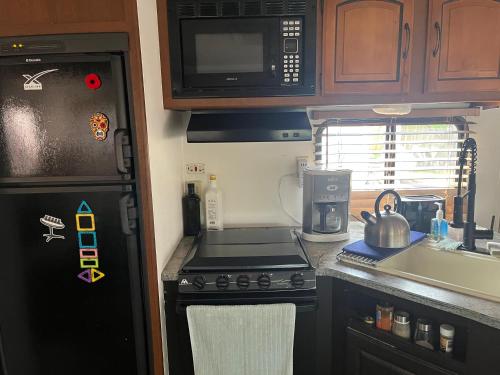 a small kitchen with a stove and a refrigerator at Comfortable Guest RV With EV charger Semi Rural Area in Bodfish